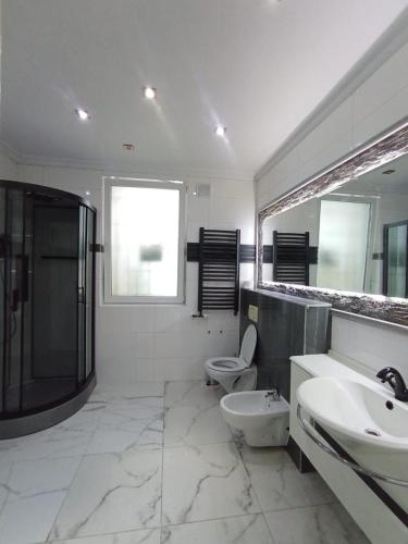 a bathroom with two sinks and a shower and a toilet at Villa Varzob ll in Warsaw