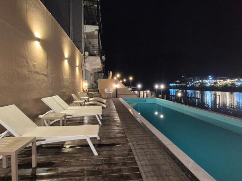 a hotel swimming pool with white lounge chairs at night at Interlaken Stay in Gapyeong