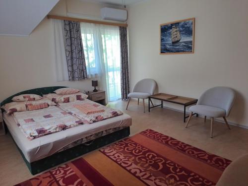 a bedroom with a bed and two chairs and a table at Holiday Home Scamard in Zamárdi