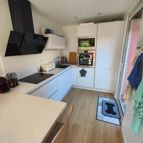 une cuisine avec des armoires blanches et un comptoir dans l'établissement Les muriers, à Canet