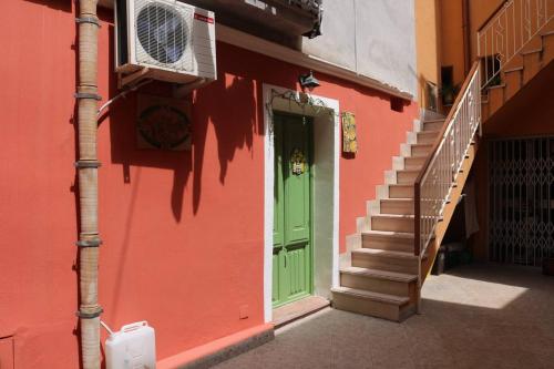 a green door on a pink building with stairs at CASA DOLCE VITA di DeNi in Marsala