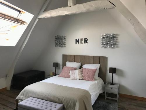 une chambre avec un lit avec des oreillers roses dans l'établissement Bienvenue aux Bateliers, à Saint-Valery-sur-Somme
