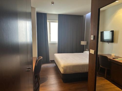a small hotel room with a bed and a television at Carris Cardenal Quevedo in Ourense