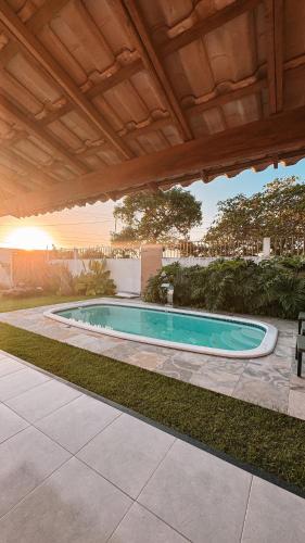 a swimming pool in a yard with a wooden roof at Lençóis Maranhenses - Casa Armonia in Santo Amaro