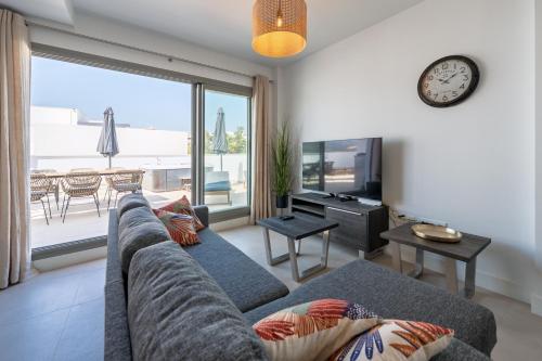 a living room with a couch and a clock on the wall at Ático Green Life by Solset in Vélez-Málaga