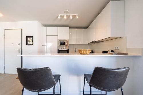 two chairs in a kitchen with white cabinets at Ático Green Life by Solset in Vélez-Málaga