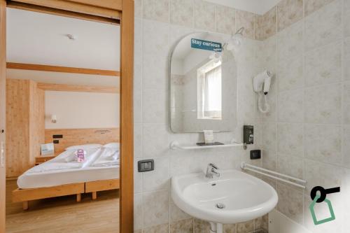 a bathroom with a sink and a mirror and a bed at Hotiday Bormio Valdidentro in Bormio