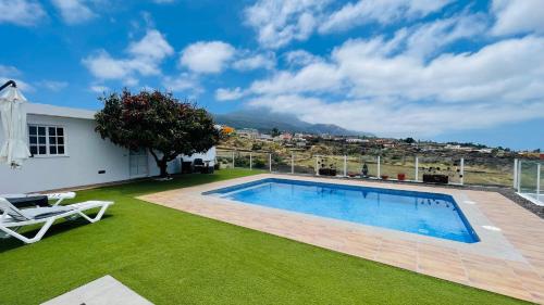 a backyard with a swimming pool and green grass at El Mirador de El Paso - vistas y piscina in El Paso