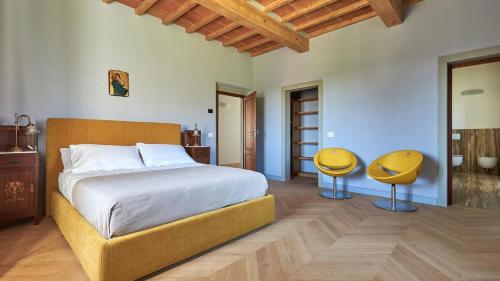 ein Schlafzimmer mit einem Bett und zwei gelben Stühlen in der Unterkunft Villa Marino in Terranuova Bracciolini
