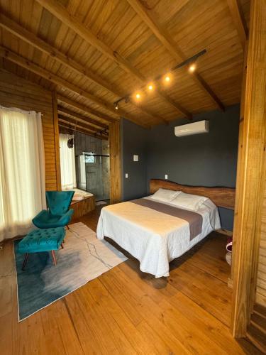 a bedroom with a bed and a blue chair at CABANA AURORA com passeios a cavalo gratuito in Urubici