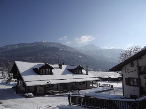 a building covered in snow with mountains in the background at Appartamento Adamello 14 in Pinzolo