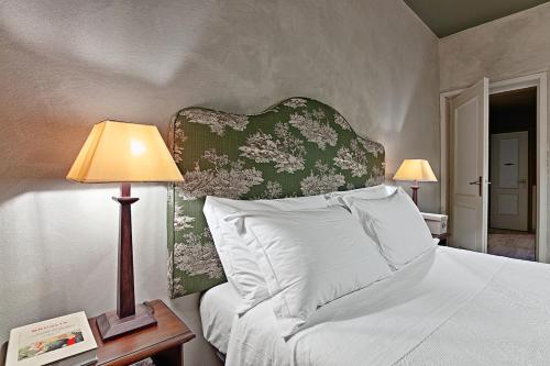 a bedroom with a bed with a headboard and two lamps at La Meirana - Cottage delle Vigne in Gavi