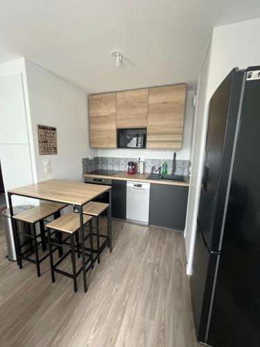 une petite cuisine avec une table et un réfrigérateur dans l'établissement T2 Cosy avec Terrasse et Jardinet, à La Rochelle