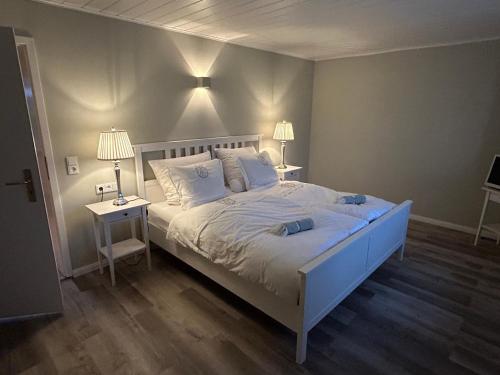 a bedroom with a large white bed with two lamps at Ferienwohnung Captains Lodge Steinbergkirche in Steinbergkirche