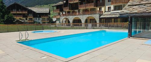 une grande piscine bleue devant un immeuble dans l'établissement l'Alpaga, à Lanslebourg-Mont-Cenis