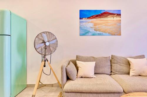 a living room with a couch and a fan at Weybeach 6 - new, modern, stylish, fully equipped in La Santa