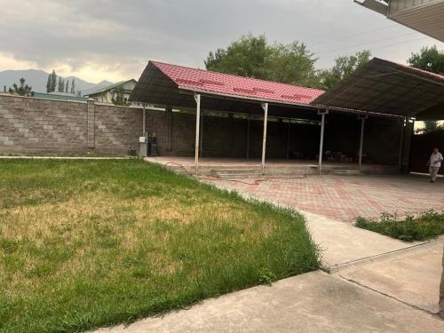 a building with a red roof and a grass field at Гостевой дом in Bishkek