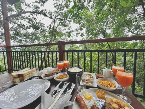 a table with plates of food and glasses of orange juice at Trance rabara resort in Avissawella