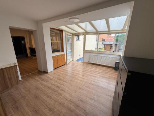 an empty living room with a wooden floor and a large window at Sunlit Apartment with Garden, Next to Station, Vienna in Vösendorf