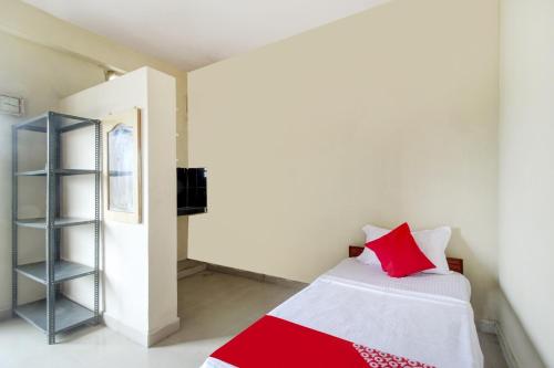 a bedroom with a red and white bed and a shelf at Hotel O HAPPY RESIDENCY in Bībīnagar