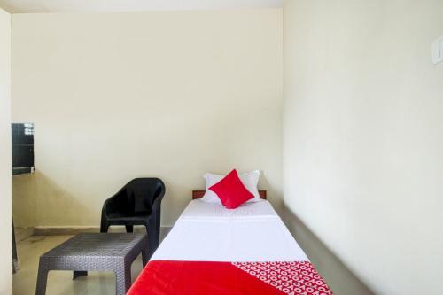 a bedroom with a bed with a red pillow and a chair at Hotel O HAPPY RESIDENCY in Bībīnagar