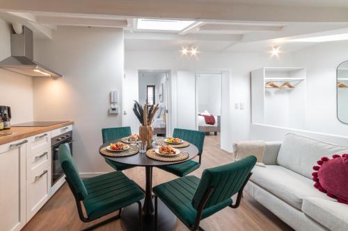 une cuisine et un salon avec une table et des chaises vertes dans l'établissement Chez Lilou et Babette 4 appartements 2 chambres, à Bruxelles