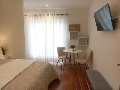 a bedroom with a bed and a table with chairs at Cozy Private Room in Nazaré - Independent Entrance - No Sharing Areas in Nazaré
