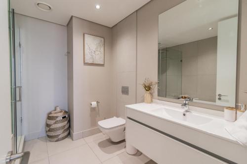a white bathroom with a sink and a toilet at Hospitality at Waterfall City - Ellipse Waterfall in Midrand
