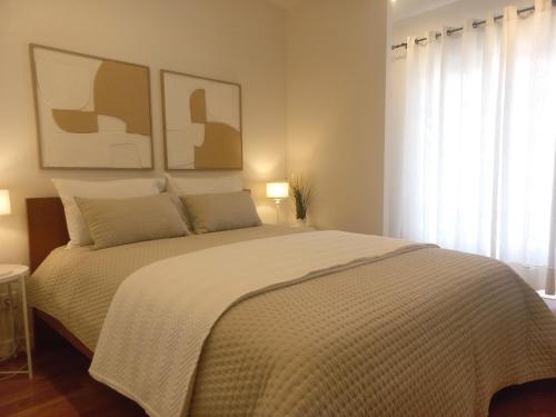 a bedroom with a large bed with two pictures on the wall at Cozy Private Room in Nazaré - Independent Entrance - No Sharing Areas in Nazaré