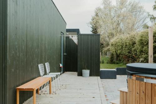 a patio with chairs and a wooden bench next to a building at Moderne Familiesommerhus Ved Hav Og Aktiviteter in Nysted