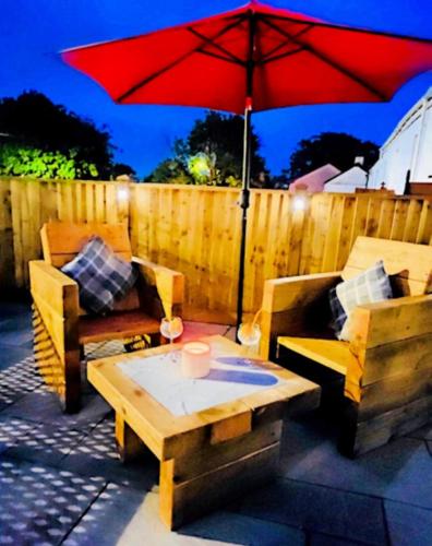 a patio with a table and a red umbrella at Holm Cottage near Charlestown in St Austell