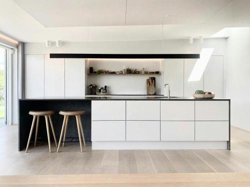 a kitchen with white cabinets and bar stools at Stylish 70'S Villa With Forest And Lake View In Ry in Ry