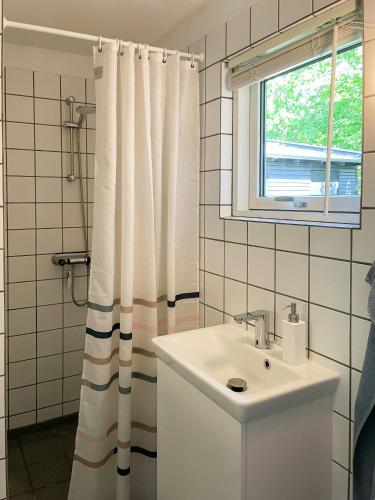 a bathroom with a sink and a shower curtain at Architect-Designed Summer House By Randers Fjord in Havndal