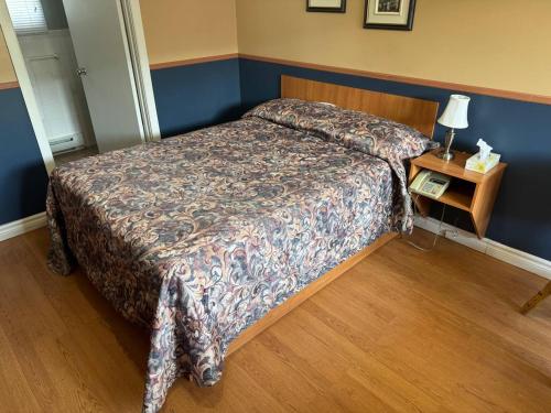 a bedroom with a bed and a table with a lamp at Auberg & Motel Moka Creme in Lévis
