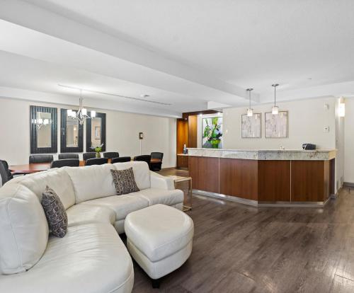 a living room with a white couch and a bar at Travelodge Hotel by Wyndham Saskatoon in Saskatoon