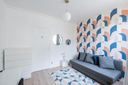 a living room with a couch and a patterned wall at Studio tout équipé proche centre ville & gare in Amiens