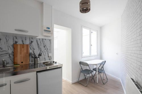 une cuisine avec des armoires blanches et une table et des chaises dans l'établissement Studio tout équipé proche centre ville & gare, à Amiens