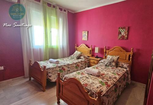 two beds in a bedroom with pink walls at Nao Santiago by Sanlúcar Housing in Sanlúcar de Barrameda