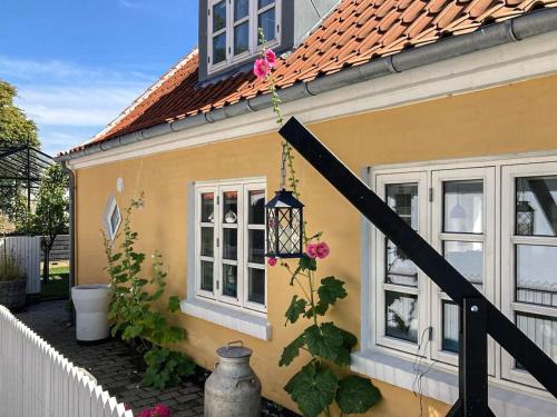 a yellow house with a lamp and flowers on it at True Skagen House From 1870 By The West Coast in Skagen