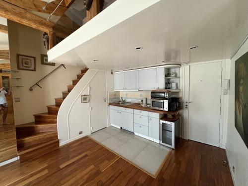 une cuisine avec des placards blancs et un escalier dans l'établissement Loft de charme proche des Halles et du Louvre, à Paris
