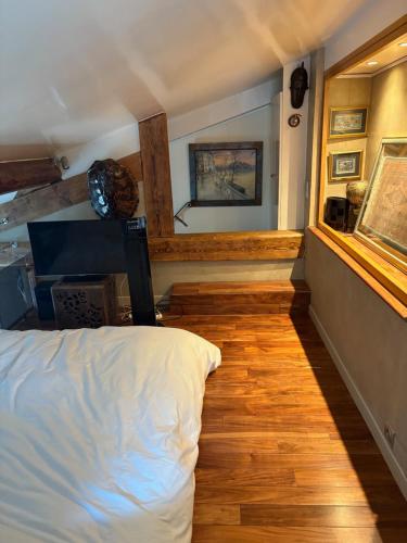 une chambre avec un lit blanc et un parquet dans l'établissement Loft de charme proche des Halles et du Louvre, à Paris