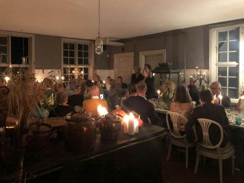 a group of people sitting at a table with candles at Historic Atmosphere At Gelskov Estate For You in Ringe