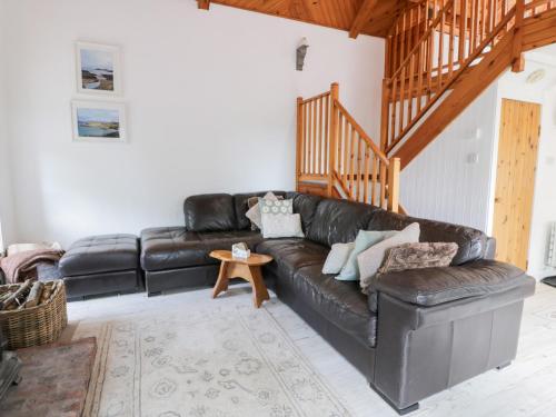 a living room with a black leather couch at The Barn in Dalbeattie