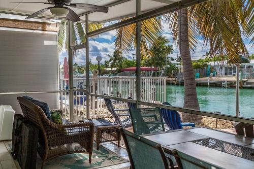 a porch with chairs and tables and a view of the water at Casita Blanca- Charming Waterfront Home, Beach Club w Pool, 30' Dock in Key Colony Beach