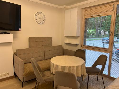 a living room with a couch and a table and a clock at Nemuno Banga in Druskininkai