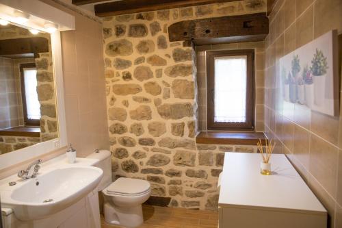 a bathroom with a sink toilet and a stone wall at Casa rural La Bárcena Saja in Saja