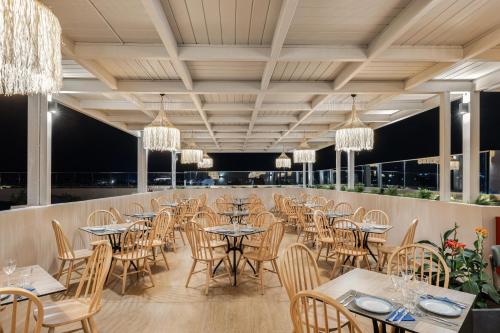 a restaurant with tables and chairs and chandeliers at White Olive Marine Aquapark in Tigaki