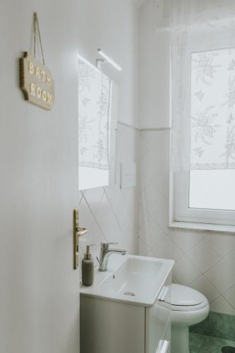 a white bathroom with a sink and a toilet at Shalom Portici in Portici