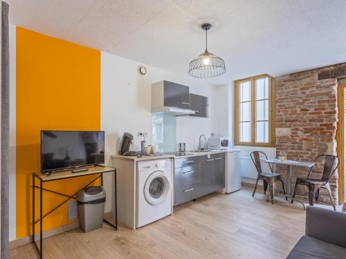 une cuisine avec une machine à laver et une table avec des chaises dans l'établissement Appartement La Violette, à Albi