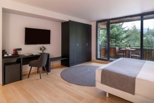 a bedroom with a bed and a desk and a television at NH Collection Andorra Palomé in La Massana